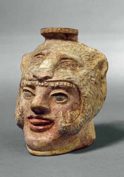 Perfume bottle, so-called aryballos, in the shape of Heracles' head wearing the lion skin. Made in Corinth. 575-550 BC.